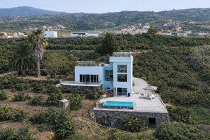 A modern two-story building with a pool on the rooftop, surrounded by greenery and hills. - Exclusive villa with views. 2 independent houses with swimming pool and private jacuzzi. (La Orotava)