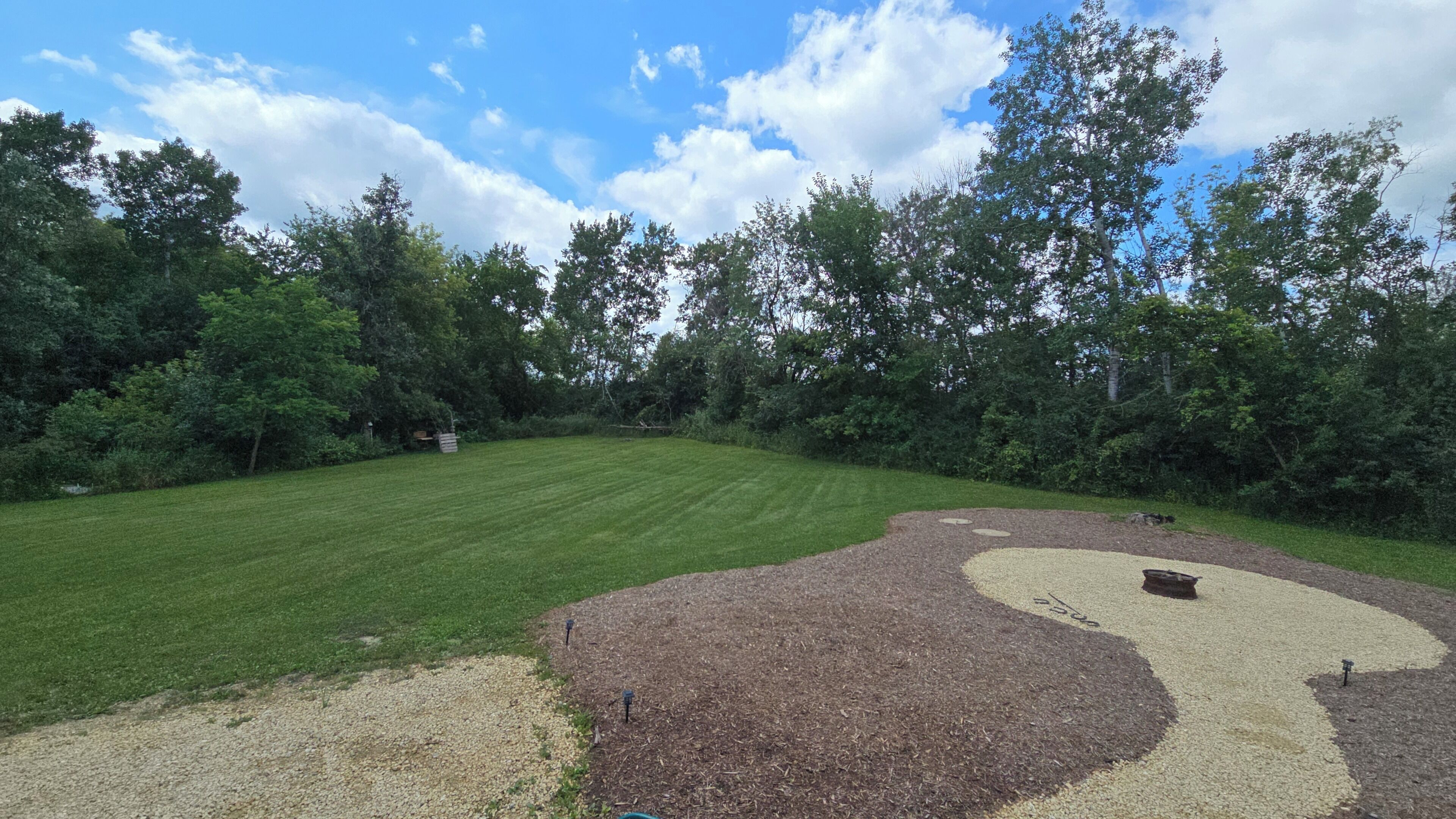 A well-maintained lawn with a gravel path and a circular garden feature.