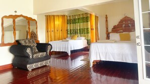 A hotel room with a wooden floor, two beds, a large mirror, and a door. - Golden Eagle/ jacuzzi/WIFI/ 20 min Airport & Beach (Montego Bay)