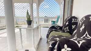 A covered outdoor seating area with a white table and chairs, a potted plant, and a view of the sea. - Golden Eagle/ jacuzzi/WIFI/ 20 min Airport & Beach (Montego Bay)