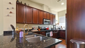 A kitchen with granite countertops, stainless steel appliances, wooden cabinets, and a stainless steel sink. - Cozy 3 bed 3 bath townhome with pool & hut tub.  Best location in Houston! (Houston)