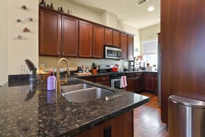 A kitchen with granite countertops, stainless steel appliances, wooden cabinets, and a stainless steel sink. - Cozy 3 bed 3 bath townhome with pool & hut tub.  Best location in Houston! (Houston)