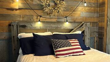 A bed with a quilt featuring a geometric pattern, a wall with a wooden plank design, and a string of lights.