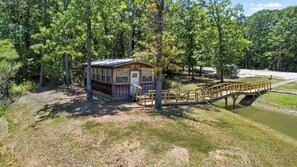 A small cabin with a wooden deck and a bridge over a water channel.
