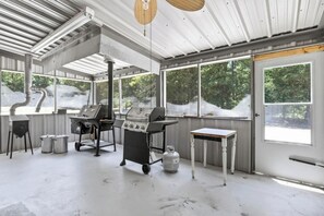 A spacious indoor area with large windows, a grill station, and a small table.
