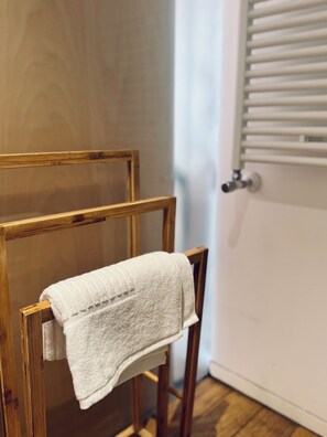 A wooden chair with a white towel draped over it, positioned next to a radiator. - Best Stay-Corso Italia Suite (Bari)
