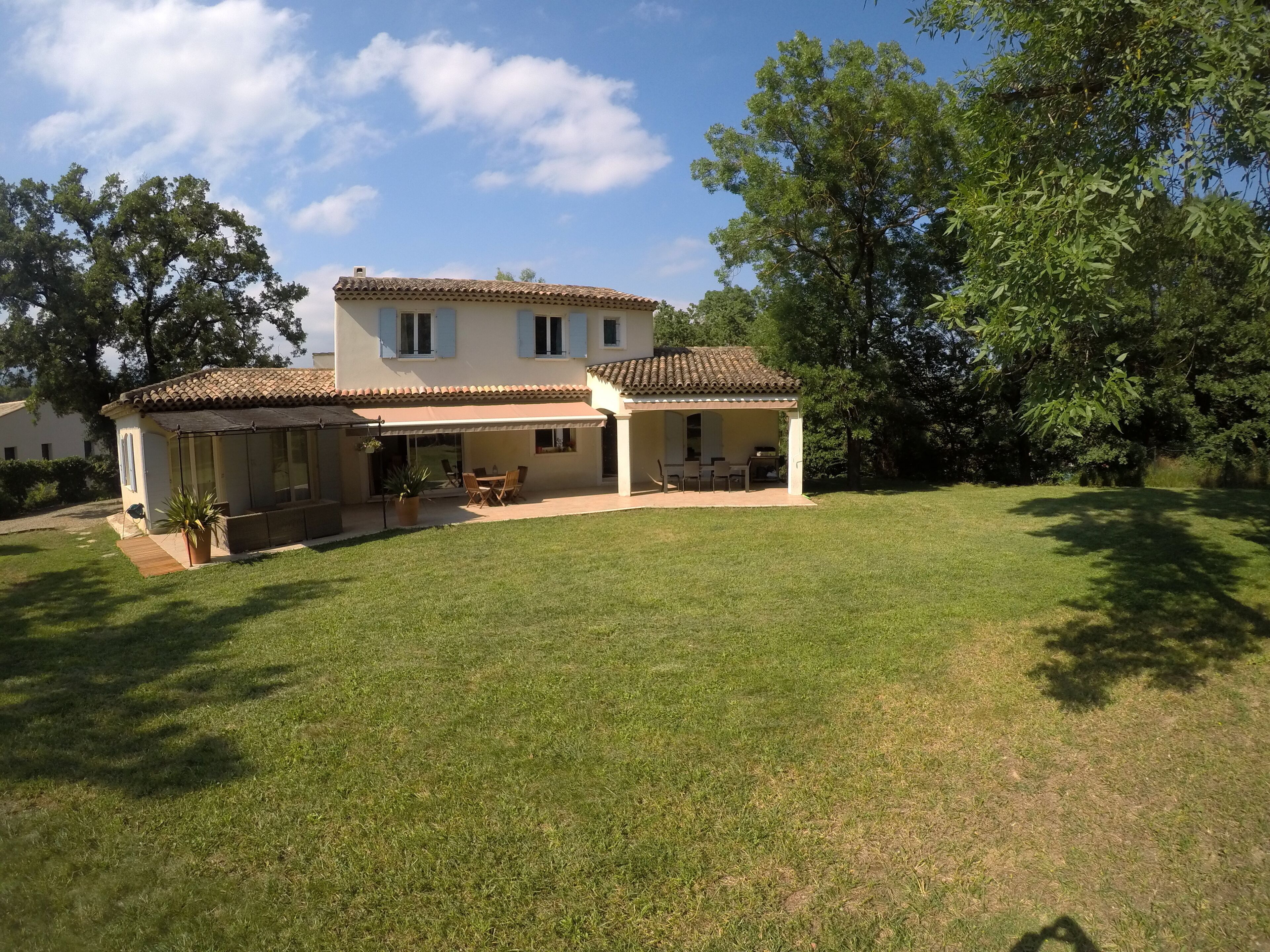 A two-story house with a patio, a covered outdoor seating area, and a lawn.