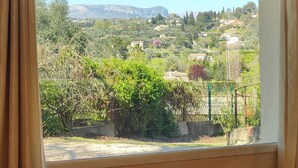 Una habitación con un ventanal grande que ofrece vistas a un paisaje montañoso con árboles y edificios.