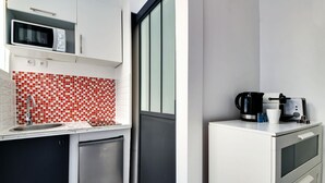 A compact kitchen with a microwave, coffee maker, and a small refrigerator. - APPARTEMENT PARIS 10eme CANAL ST MARTIN (Paris)