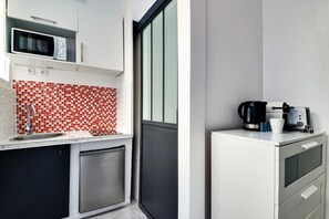 A compact kitchen with a microwave, coffee maker, and a small refrigerator. - APPARTEMENT PARIS 10eme CANAL ST MARTIN (Paris)