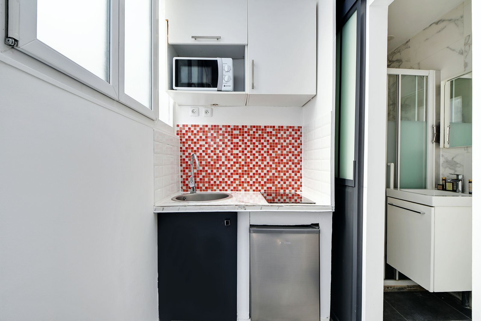 A compact kitchen with a microwave, sink, and dishwasher.