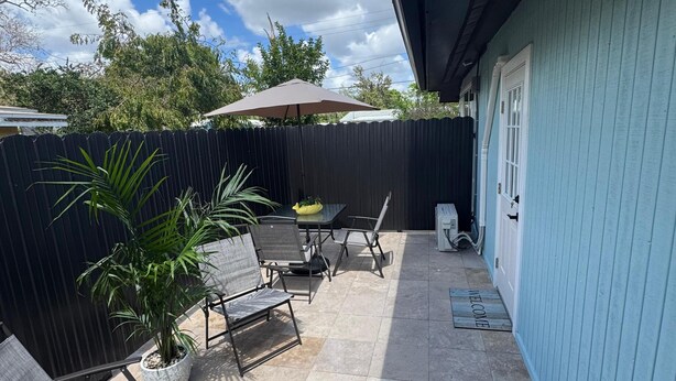Eine Terrasse mit Gartenmöbeln, einer Fußmatte und Blick zum Himmel.