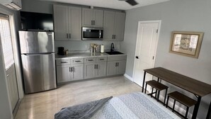 Eine kleine Küche mit Kühlschrank, Mikrowelle und Schränken.