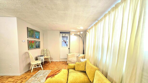 A living room with a yellow sofa, a white chair, a small table, and a lamp. - Cozy haven (Toronto)
