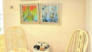 A room with four framed artworks on the wall, two wooden chairs, and a small table with a tray of items. - Cozy haven (Toronto)