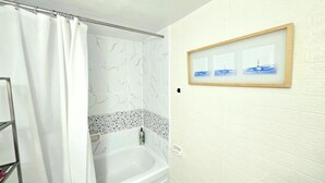 A bathroom with a bathtub, shower curtain, marble wall, and a framed picture on the wall. - Cozy haven (Toronto)