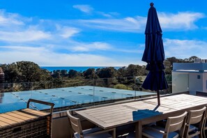 A rooftop terrace with a table, chairs, and a blue umbrella. - Del Mar Retreat w/Ocean Views, Outdoor Pool, Rooftop Deck, Near Beaches & Trails (Del Mar)