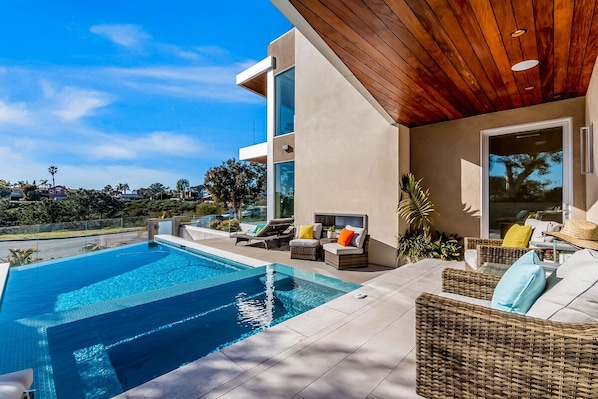 Una casa moderna con piscina, muebles de exterior y vistas al paisaje circundante.