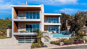 A modern two-story house with a garage, a swimming pool, and a well-maintained garden.