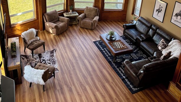 A spacious living room with large windows, a fireplace, and a high ceiling.