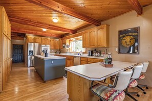 A spacious kitchen with wooden cabinets, a central island, and a dining area with a chair.