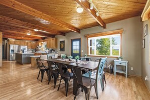 A spacious kitchen with wooden cabinets, a dining area with a large table and chairs, and a view of the outdoors through a window.