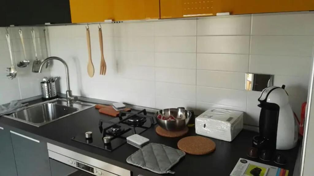 Ett modernt kök med en gasspis, en diskho i rostfritt stål och vita kakelplattor ovanför diskbänken.