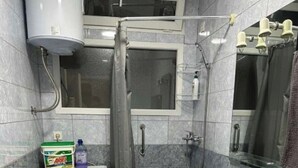 Ett litet badrum med tvättmaskin, dusch med duschdraperi, handfat och spegel.