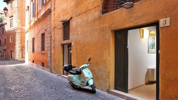 Una moto estacionada en una calle adoquinada frente a un edificio con un letrero con el número 3, indicando una dirección numerada.