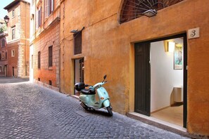 A scooter parked on a cobblestone street in front of a building with a number '3' sign, suggesting a numbered address. - Dal Charming and Modern Ground Floor Loft (Rome)