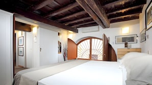 Un dormitorio con una cama, una puerta de madera y un equipo de aire acondicionado instalado en la pared.