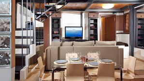 Una sala moderna con sofá, mesa de comedor, sillas y televisor.