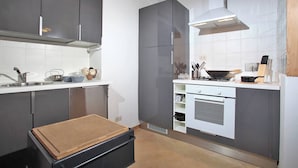 Una cocina moderna con gabinetes grises, una campana extractora de acero inoxidable y un horno empotrado.
