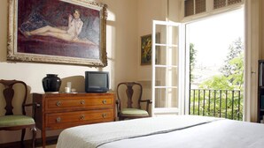 Un dormitorio con cama, cómoda, televisor, sillas y un cuadro.