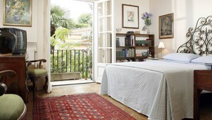 Un dormitorio con cama, una estantería, un escritorio con silla y una ventana con vistas al exterior.