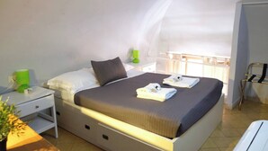 A bedroom with a bed, a nightstand, a lamp, a window with a view, and a chair. - Mir Small Loft on Giulia Street (Rome)