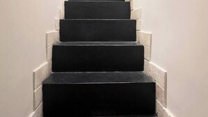 A staircase with black steps and white edges, leading to a blue door. - Mir Small Loft on Giulia Street (Rome)