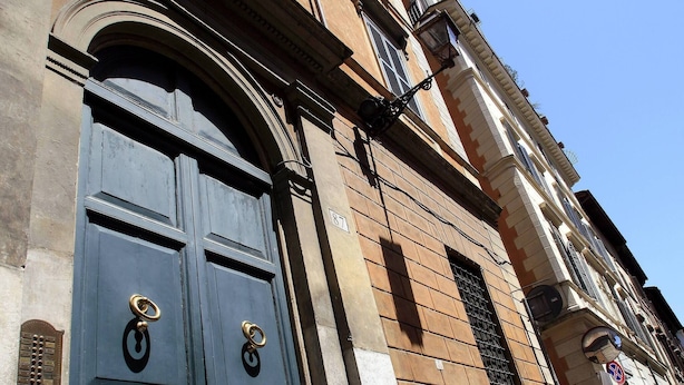 A building with a large, dark blue door with two brass handles and a small window with a metal grill. - Mir Small Loft on Giulia Street (Rome)