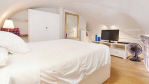 A bedroom with a bed, a TV, a mirror, and a fan. - Renoir Small Loft on Giulia Street (Rome)
