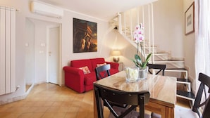 A modern living room with a red sofa, a dining table, and a staircase. - Renoir Small Loft on Giulia Street (Rome)