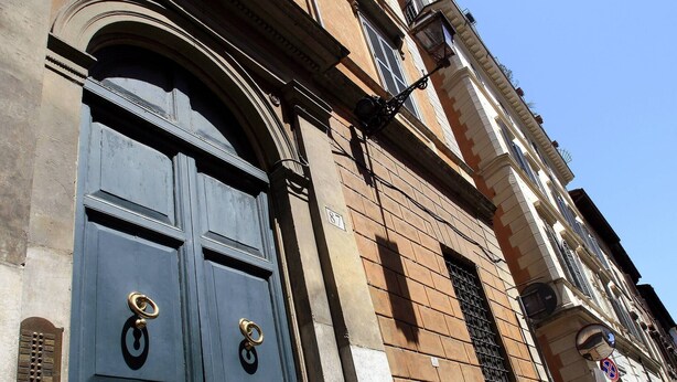 A building with a large, dark blue door with two brass handles and a small window with a metal grill. - Renoir Small Loft on Giulia Street (Rome)