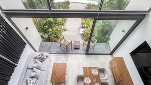 A modern interior with a glass ceiling, a sofa, a dining table set for four, and a small garden view. - Mistiq Gardens 2 (Tulum)