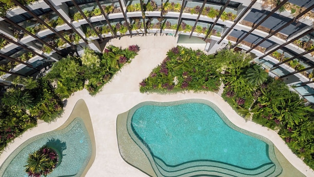 A rooftop pool with a unique design, surrounded by lush greenery and modern architecture. - Mistiq Gardens 2 (Tulum)