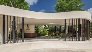 A modern building with a curved entrance, a covered area with vertical supports, and a central open space with a ceiling fan. - Mistiq Gardens 2 (Tulum)