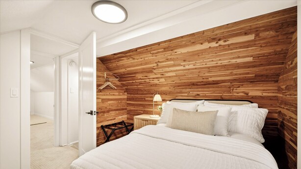 Une chambre à coucher avec une tête de lit en bois, un lit recouvert de linge de lit blanc, une table de chevet avec une lampe et une porte donnant sur une autre pièce.