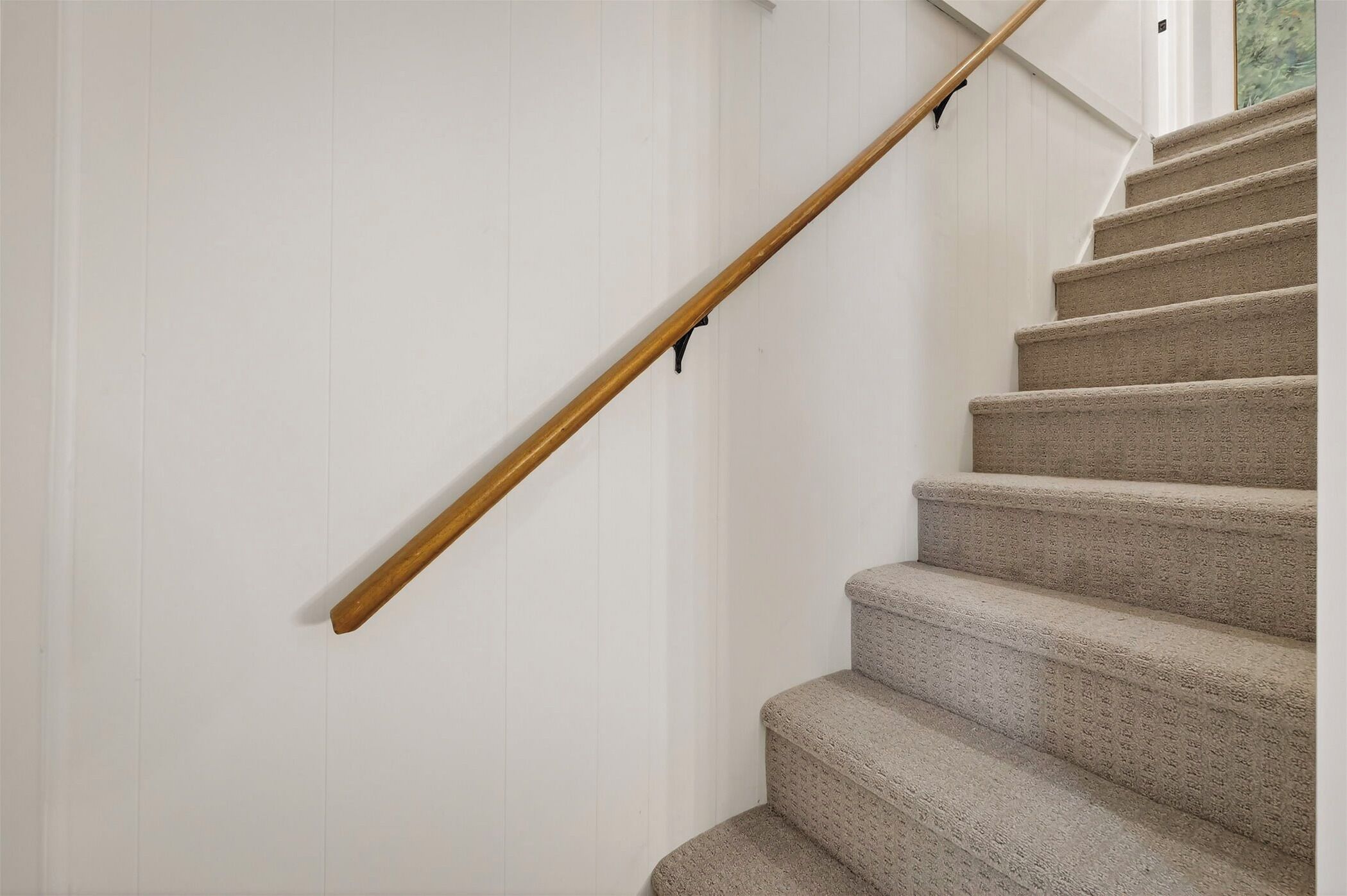 Una escalera con barandilla de madera y peldaños alfombrados.