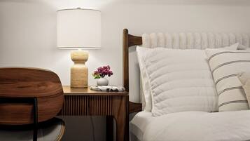 Une chambre bien rangée, avec un lit, une table de chevet, une lampe et une chaise.