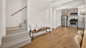 Une cuisine moderne dotée d’appareils électroménagers en acier inoxydable, d’un banc en bois et d’un escalier avec une rampe en bois.