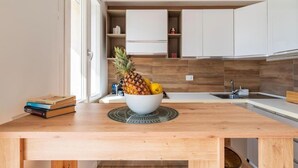Una cocina moderna con armarios blancos, encimera de madera y un cuenco de fruta.