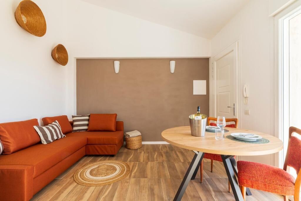 A modern living room with a sectional sofa, a round dining table, and a large window.
